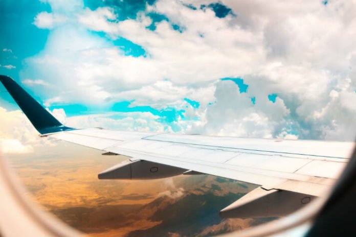 view from plane window of sky, clouds and ground