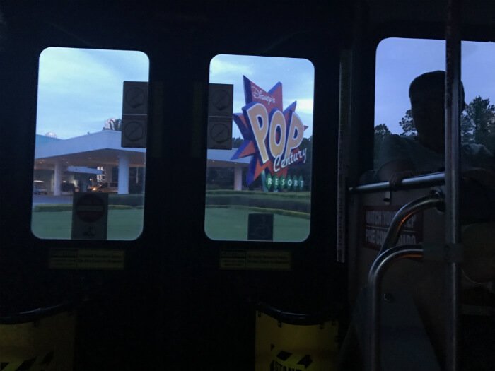 inside Disney bus with view through window of Disney's Pop Century Resort sign