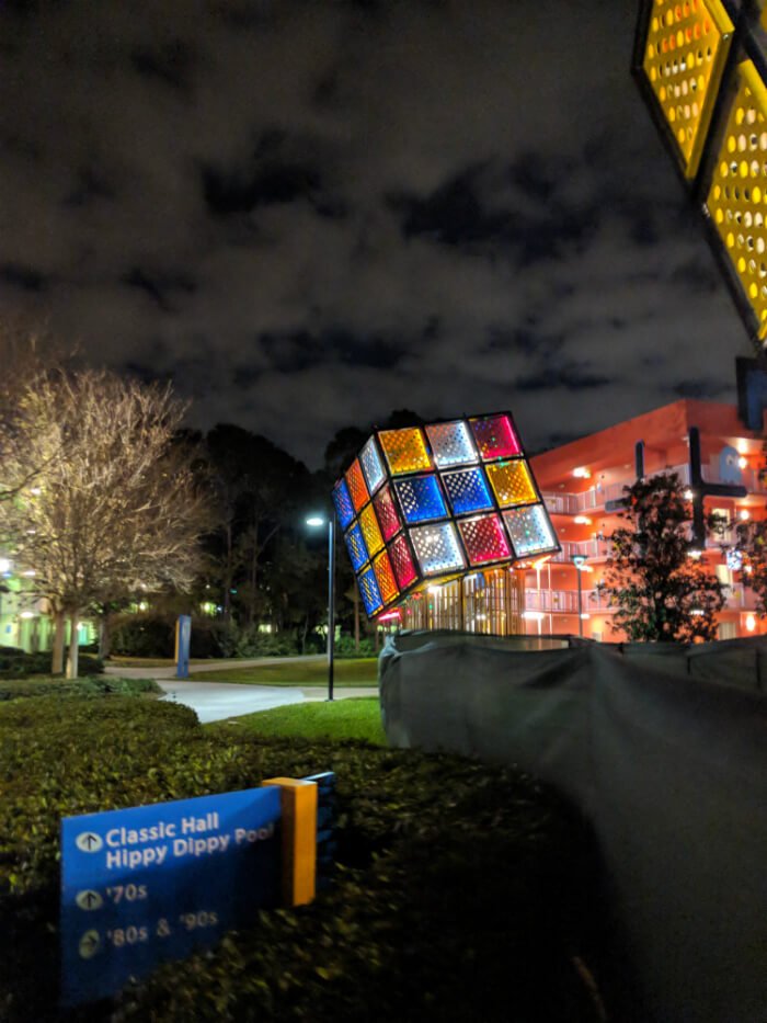 Disney's Pop Century Resort at night with giant Rubik's Cube & sign for Classic Hall, Hippy Dippy Pool, 70s, 80s, 90s sections