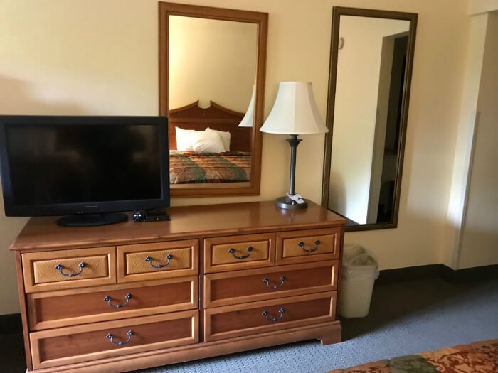 inside hotel room at Country Inn & Suites Williamsburg with dresser, tv, lamp