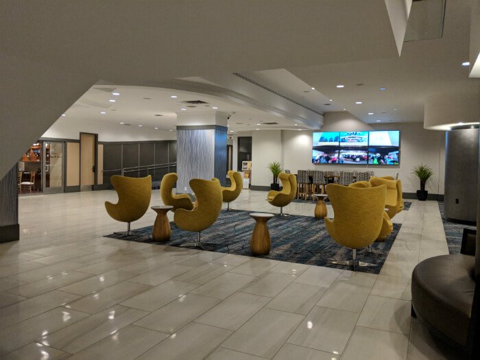 Wyndham Grand Pittsburgh Downtown lobby with yellow chairs, several TVs and open space