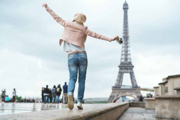 Picture of a happy tourist visiting Paris, France. Find out how you can get a free trip to Paris